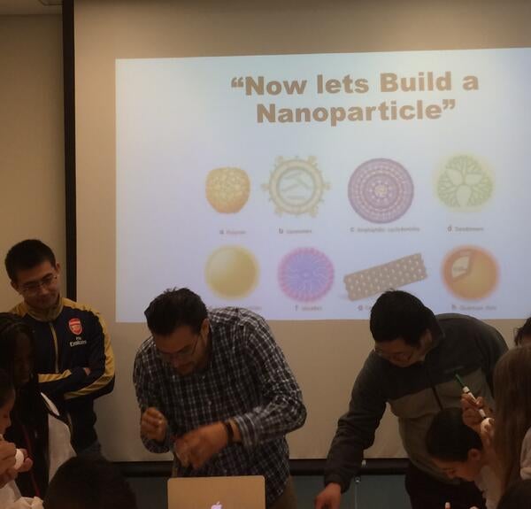 Three male scientsits standing in front of a slide that states "Now lets build a Nanoparticle"