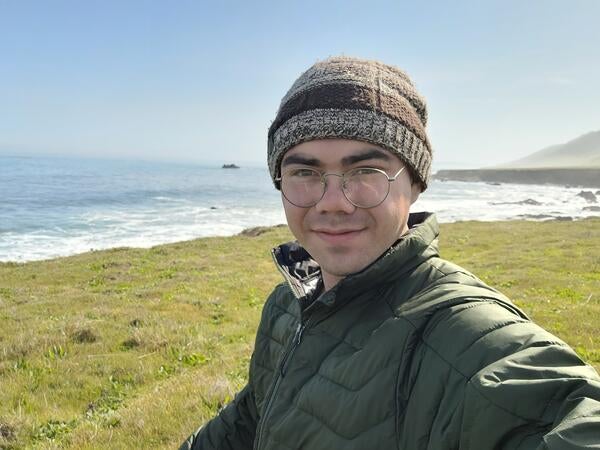 Photo of person standing in front of shoreline next to grassy field