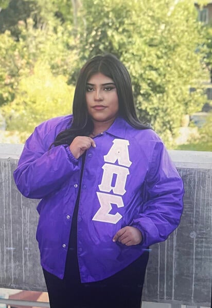 Leslie standing with letterman jacket