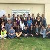 Group photograph of the volunteers for Plant Discovery Day- 3 rows of people standing in front of a Plant Discovery Day banner